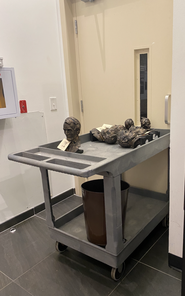 sculptures of abe lincoln busts on a grey cart in front of a door